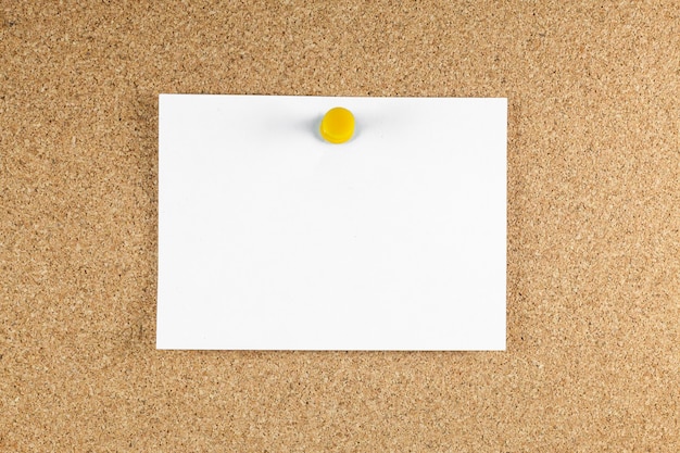 Blank white note papers is pinned to a cork board.