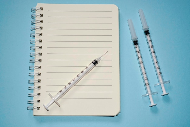 Blank white notepad with disposable injection syringes. Journal and medication concept