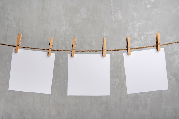 Blank white notes of paper hang with clothespins on rope