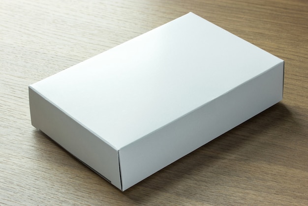 Foto scatola di carta bianca vuota su sfondo scuro di legno