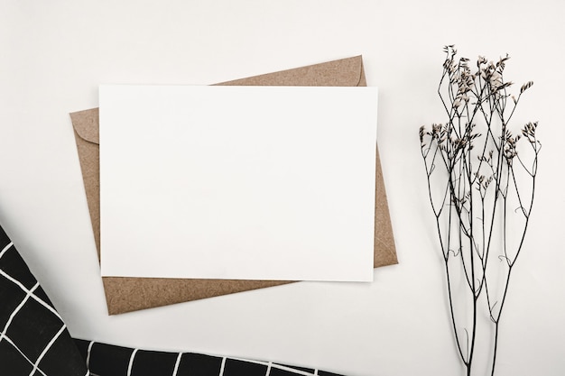 Photo blank white paper on brown paper envelope with limonium dry flower and and black cloth white grid