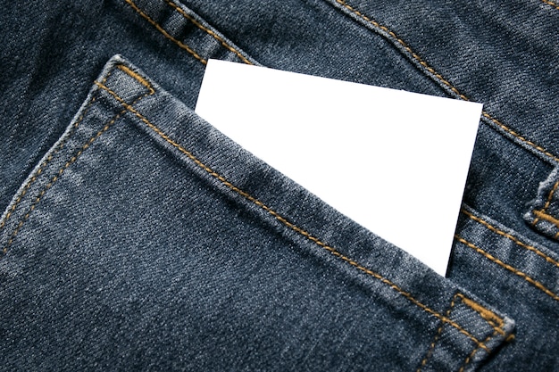 Blank white paper or card in back pocket of blue jeans with copyspace for sale text or business concept