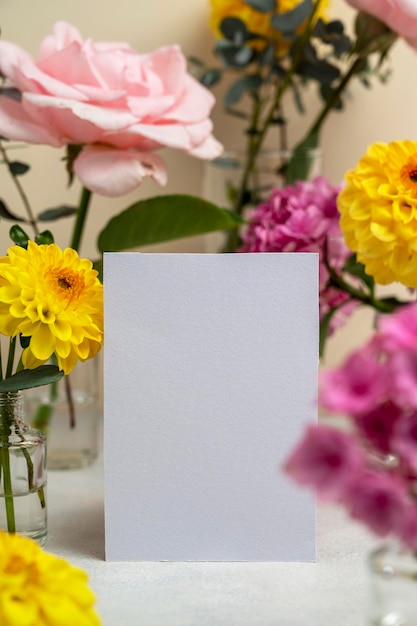 Blank white paper greeting card mock up Pink and yellow flowers in vases with copy space Hydrangea dahlias and eucalyptus