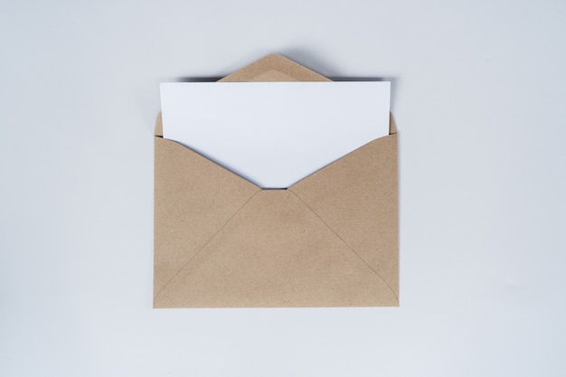 빈 백서는 열린 갈색 종이 봉투에 놓입니다. 흰색 바탕에 공예 종이 봉투의 상위 뷰.