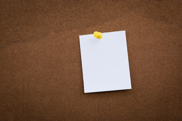 Blank white paper note pinned on cork board with white thumbtacks, copy space available