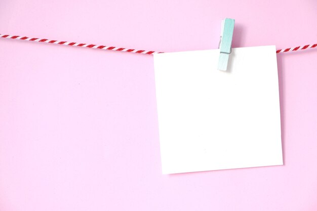 Blank white paper notepad hanging on pink background, with copy space for text