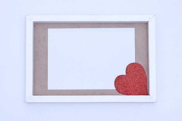 Blank white paper with red heart on a wooden frame. Mock-up of horizontal blank greeting card on whi