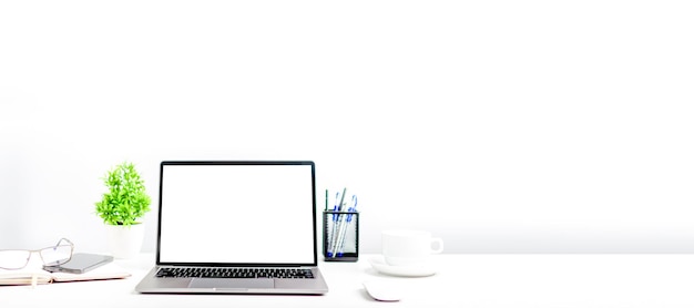 オフィスの白いテーブルに白いスクリーンノートパソコンを使用した作業コンセプト ノートパソコンのスマートフォン デバイス デザインやテキストのために右のスペースをコピー クローズアップ 灰色とぼやけの背景