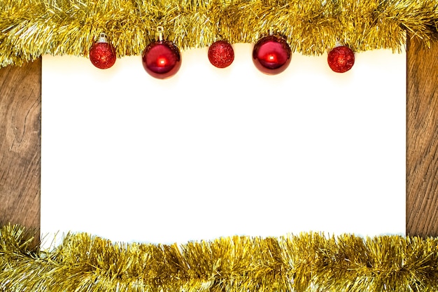 Blank white sheet of paper with gold tinsel and red Christmas balls. Flat lay style. Copyspace.