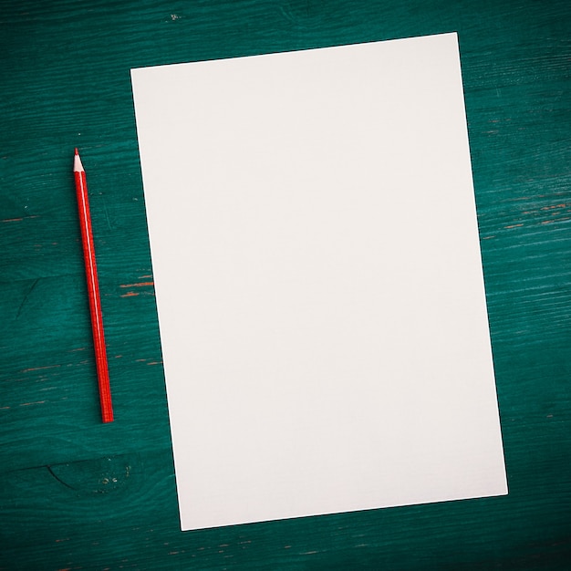 A blank white sheet and pencil for drawing on a wooden background