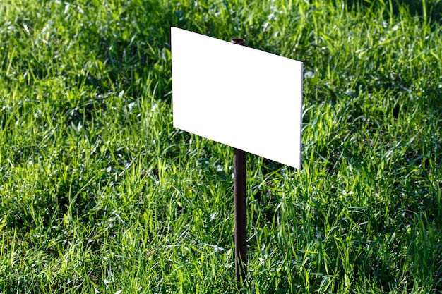 Foto mockup bianco vuoto del segno sul primo piano verde del fondo del prato inglese con il fuoco selettivo