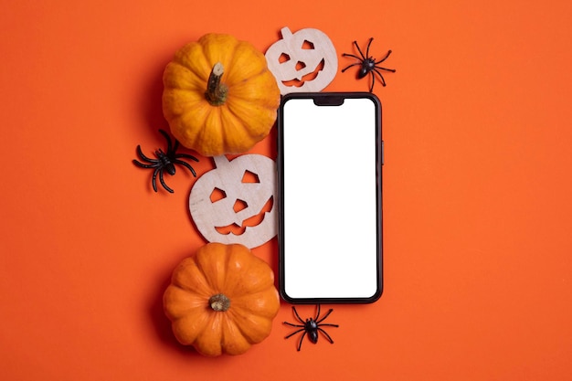 Foto schermo dello smartphone bianco vuoto con zucche e ragni
