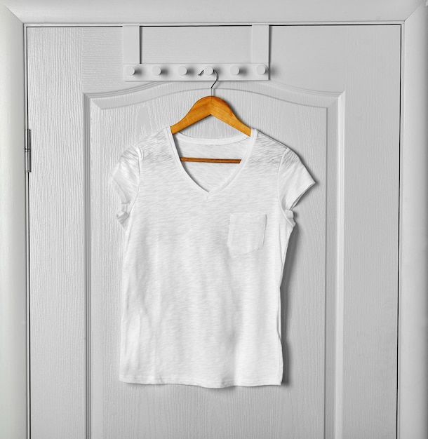 Blank white t-shirt hanging on door