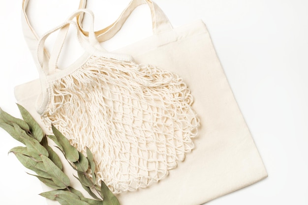 A blank white tote bag and a cotton mesh bag on a white background