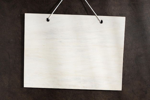 写真 暗いテクスチャ壁にぶら下がっている空白の白い木製看板モックアップテンプレート