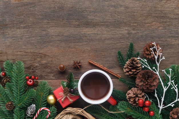 Blank wood plank decorate with pine leaf, pine cones, holly balls, candy cane and red cup chocolate.