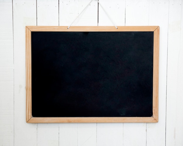 Blank wooden slate hanging on white wall