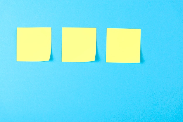 Blank yellow sticky notes on blue 