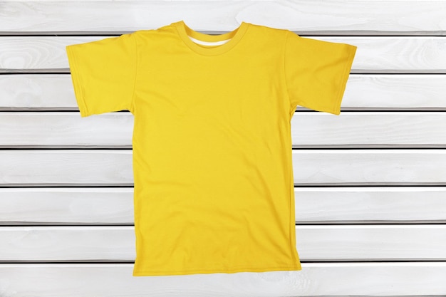 Blank yellow t-shirt on wooden background