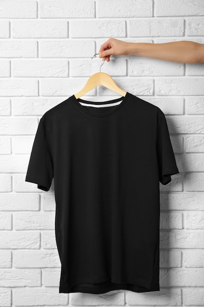 Blank zwart T-shirt tegen bakstenen muur