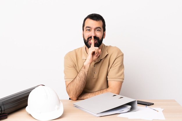 Blanke architect man met baard in een tafel met een teken van stilte gebaar vinger in de mond steken.