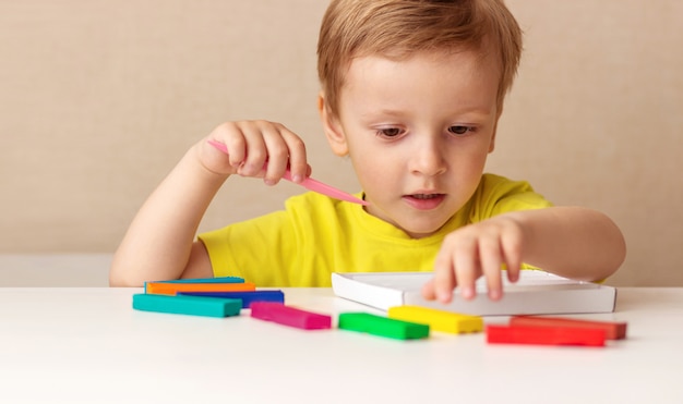 Blanke babyblonde beeldhouwen uit kinderdeeg voor thuis beeldhouwen aan tafel, kinderen en creativiteit, de ontwikkeling van fijne motoriek