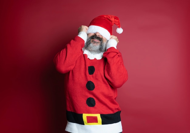 Blanke bebaarde man met de kerstman is een te grote hoed voor hem