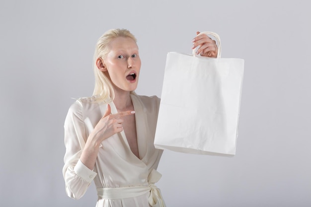 Blanke blanke albino-blonde vrouw houdt zwarte boodschappentassen Verkoop en kortingen op de markt en Black Friday-concept