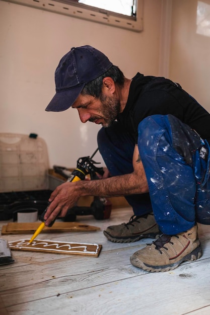 blanke blanke man die universele lijm op hout aanbrengt voor het interieur van zijn camper. Camper