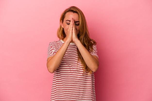 Blanke blonde vrouw geïsoleerd op roze achtergrond hand in hand in bidden in de buurt van mond, voelt zich zelfverzekerd.