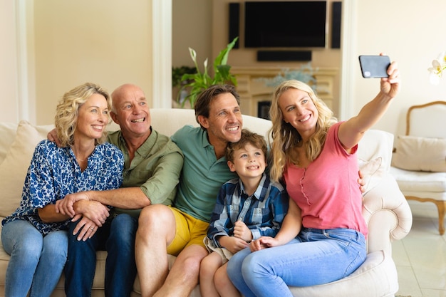 Blanke familie van drie generaties die een selfie maakt terwijl ze thuis samen op de bank zitten. sport- en entertainmentconcept, ongewijzigd.