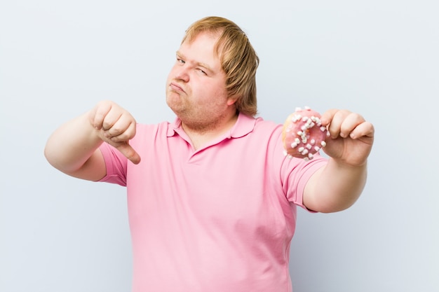 Foto blanke gekke blonde dikke man met een donuts