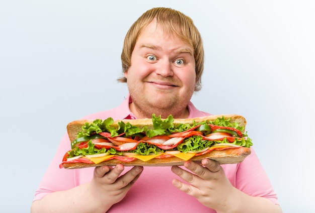 Blanke gekke blonde dikke man met een gigantische sandwich