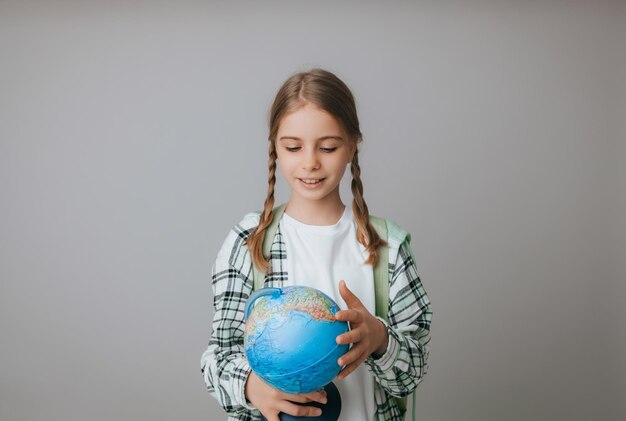 Blanke jonge tiener schoolmeisje student houdt een wereldbol op een grijze achtergrond geïsoleerd Happy earth day