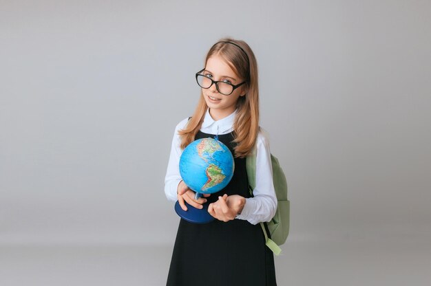 Blanke jonge tiener schoolmeisje student houdt een wereldbol op een grijze achtergrond geïsoleerd Happy earth day