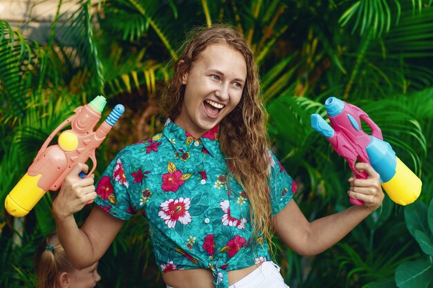 Blanke jonge vrouw is klaar om te vechten met een waterpistool op het Songkran-festival. Vakantie concept