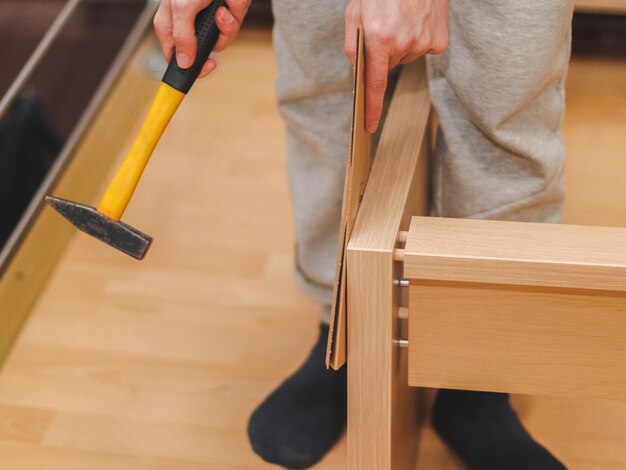 Blanke jongeman hamert houten spijkers met een gele hamer