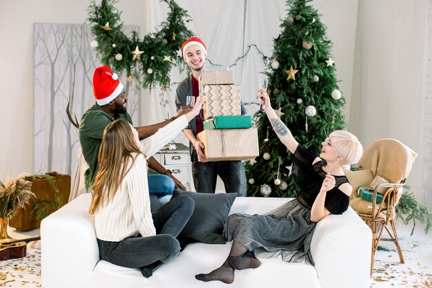 Blanke jongeman presenteert kerstcadeaus aan vrienden op de bank op nieuwjaarsfeest