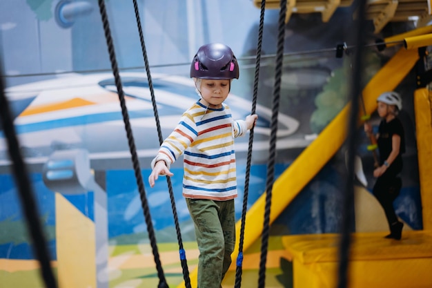 Blanke jongen klimmen in avonturenpark passeren hindernisbaan touwenparcours binnenshuis