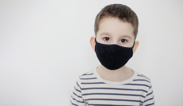 Blanke jongen met een zwart gezichtsmasker die naar de camera kijkt op een witte achtergrond kopieerruimte voor tekst