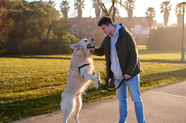 Blanke jongen speelt met een golden retriever-hond in een groen park