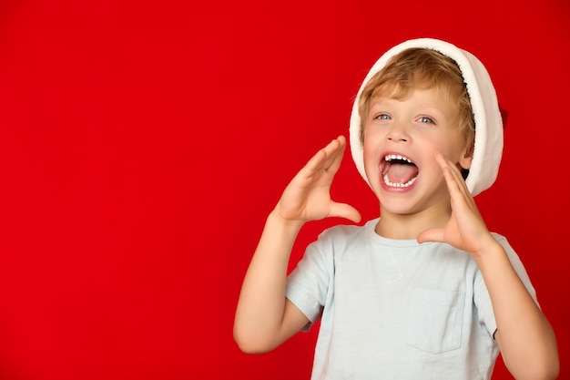 Blanke kleine jongen schreeuwt met een blij blij gezicht op een rode achtergrond