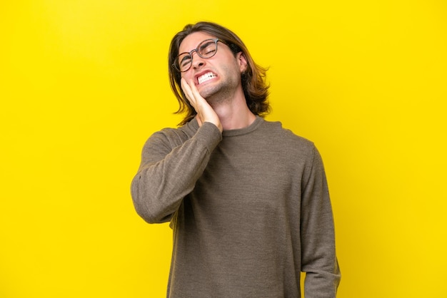 Blanke knappe man geïsoleerd op gele achtergrond met kiespijn