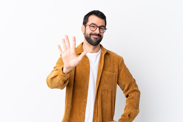 Blanke knappe man met baard draagt een corduroy jas over wit tellen vijf met vingers