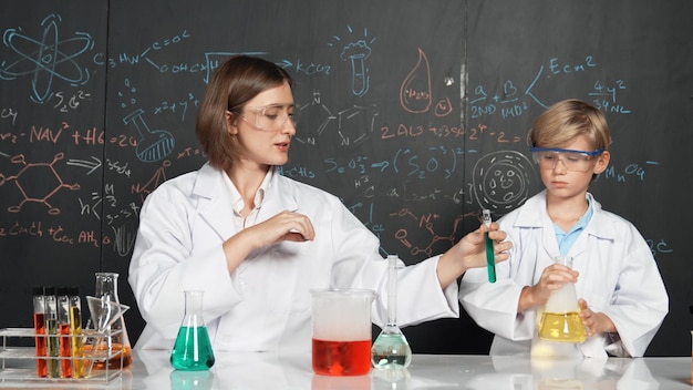 blanke leraar helpt student gemengde vloeistof in wetenschap laboratorium Eruditie