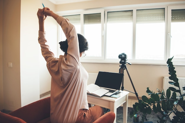 Foto blanke leraar klaar voor de online lessen op de computer met een boek en een moderne camera vooraan