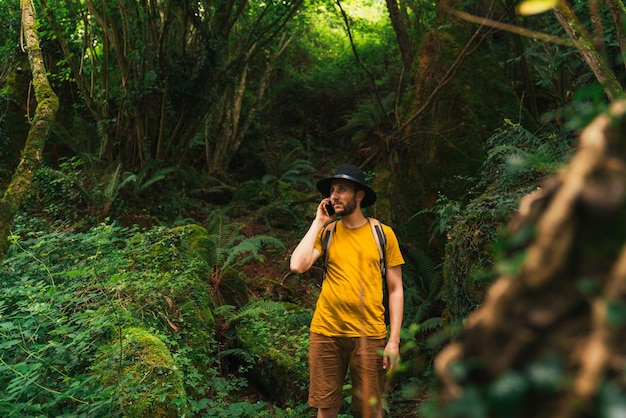 Blanke man aan de telefoon in het midden van de jungle op een zonnige dag.