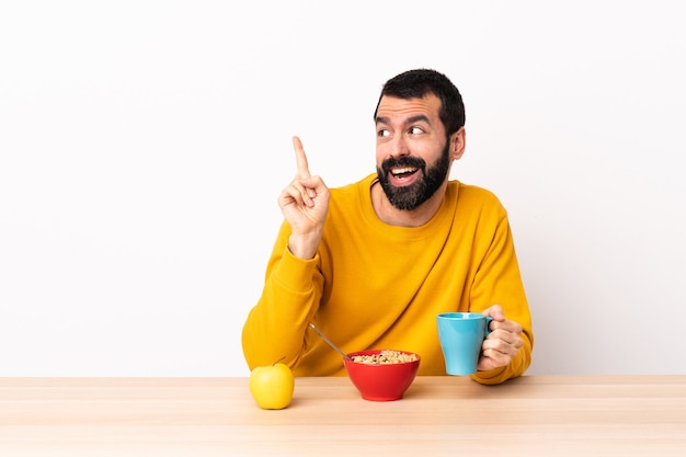 Blanke man aan het ontbijten in een tafel die de oplossing wil realiseren terwijl hij een vinger opheft.