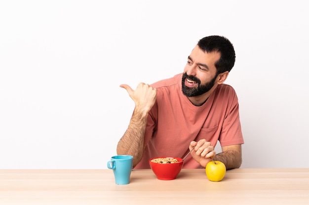 Blanke man aan het ontbijten in een tafel die naar de zijkant wijst om een product te presenteren.