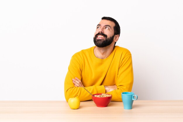 Blanke man aan het ontbijten in een tafel opzoeken terwijl lachend.